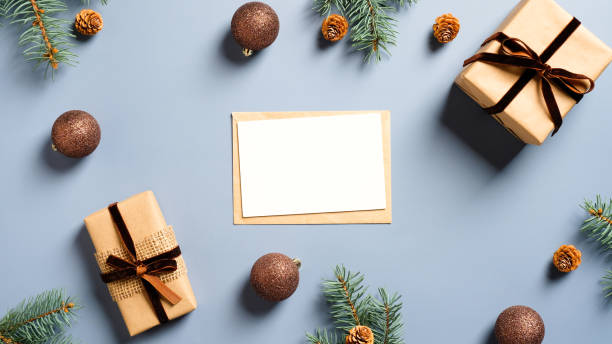 istock Blank Christmas card mockup, envelope, Xmas gifts, decorations, pine branches on pastel blue background. Flat lay, top view. Christmas, New Year, winter holidays concept. 1288427309