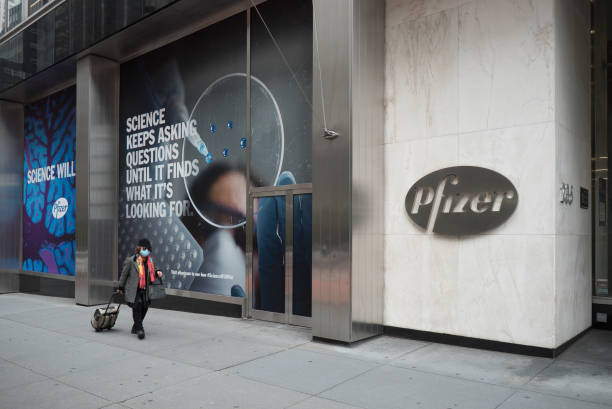 New York during the COVID-19 emergency. Manhattan, New York. November 27, 2020. A woman walks in front of Pfizer headquarter in Midtown. pfizer stock pictures, royalty-free photos & images