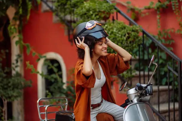 An attractive young woman preparing to ride her vespa through the city