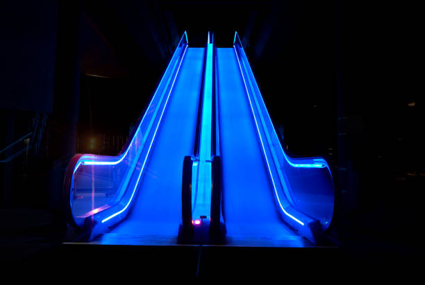 Blue illuminated escalator at night with intentional motion blur of the escalator steps