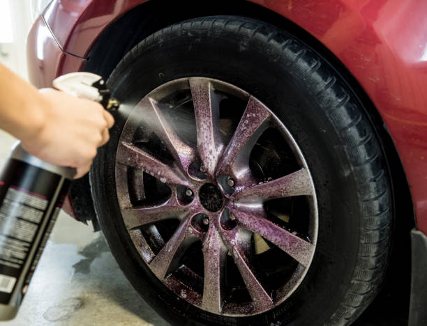 istock Service worker washing car wheell at a car wash. 1288431679
