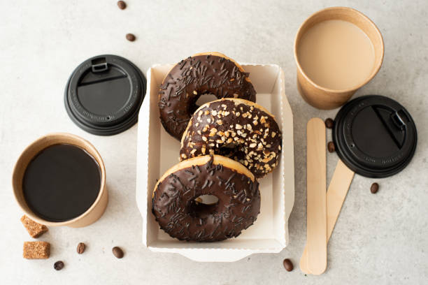 istock chocolate donuts with glaze in a craft box and black coffee in cups 1288431783