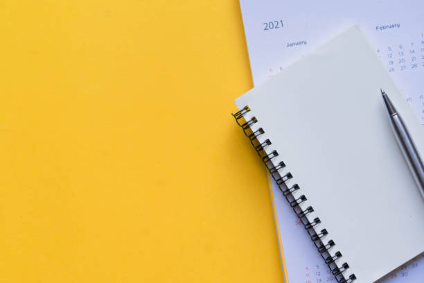 закрыть верхний вид на пустой странице ноутбука с календарем 2021 график и перо на желтом цветном фоне, чтобы сделать встречу назначения или � - photography chance aspirations yellow стоковые фото и изображения