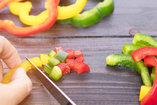 pimienta de campana cortante a mano sobre fondo rústico de mesa de madera. (enfoque selectivo) - chopped green bell pepper pepper bell pepper fotografías e imágenes de stock