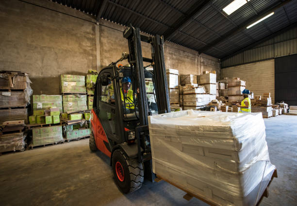 istock Wide angle image of forklift lifting construction material with a woman working in the background.construction workers image 1288436845