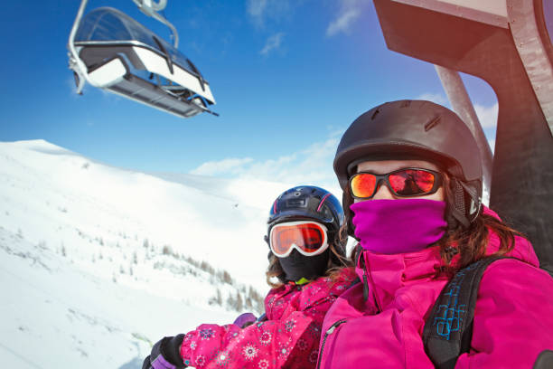 Two skiers going on ski lift Passengers going on ski lift with face masks during covid-19 pandemic overhead cable car photos stock pictures, royalty-free photos & images