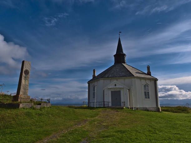 beautiful historic wooden dverberg church (dverberg kirke) constructed in octagonal style and white colored facade with stone monument on sunny day. - scandinavian church front view norway imagens e fotografias de stock