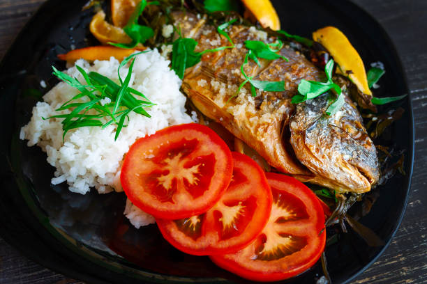 istock Fried dorada with aromatic herbs, lemon and rice garnish and sliced tomatoes 1288438869