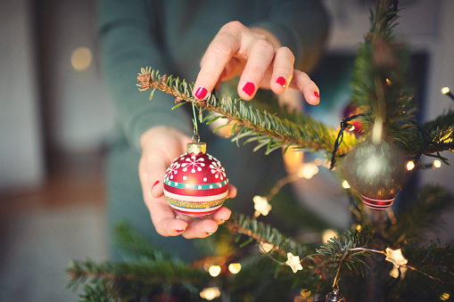 Attractive woman decorates the Christmas tree
