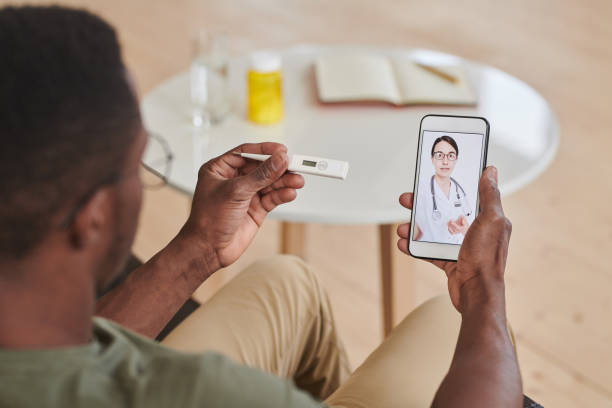 istock Unrecognizable African American man checking body temperature while consulting his doctor online using smartphone 1288439673