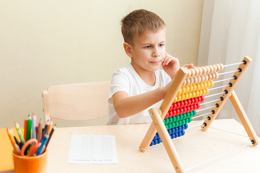 child solving maths exercises. 7 years old boy doing maths lessons sitting at desk in his room.