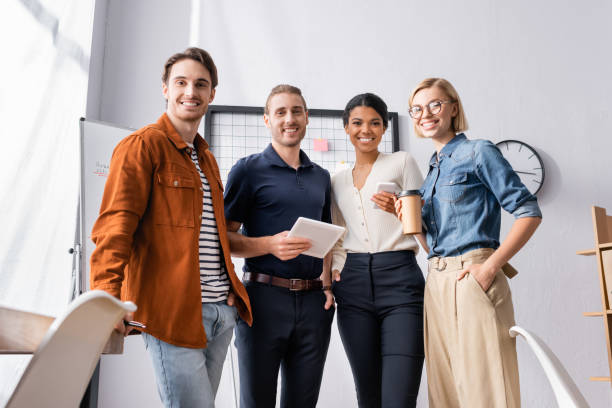 istock happy, young multicultural businesspeople looking at camera in office 1288442101