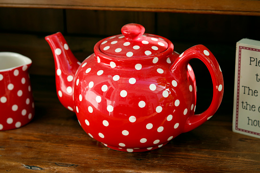 A photograph of a red tea pot on wooden table.