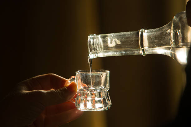 палинка, знаменитый венгерский алкоголь, льется из бутылки в стекло. - hungarian culture стоковые фото и изображения