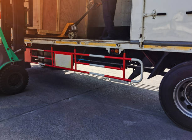 istock Worker driving forklift loading shipment carton boxes goods on wooden pallet at loading dock from container truck to warehouse cargo storage in freight logistics, transportation industrial, delivery 1288446205