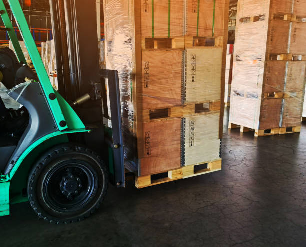 istock Worker driving forklift loading shipment carton boxes goods on wooden pallet at loading dock from container truck to warehouse cargo storage in freight logistics, transportation industrial, delivery 1288446242