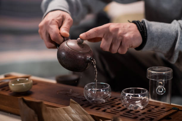 木製のトレイに熱い芳香族茶充填カップと伝統的なセラミックティーポットのクローズアップ。ぼやけた背景 - tea chinese tea heat teapot ストックフォトと画像