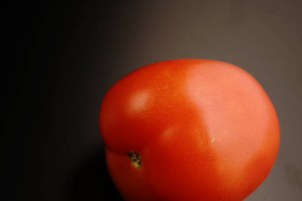 istock Red fresh tomato. Mature. Dimmed light. On black background. 1288447241