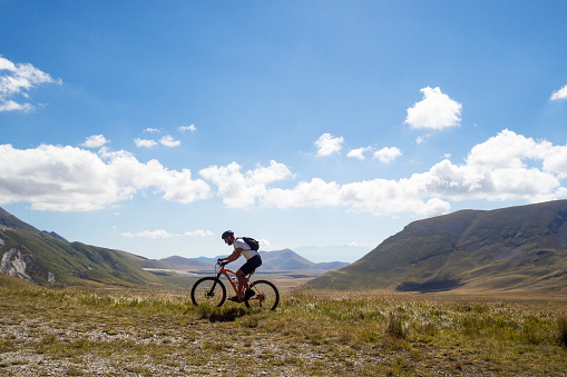 Side view of an adult mountain biker riding his bicycle on a mountain trail of the Abruzzi National Park. Campo Imperatore, Italy.