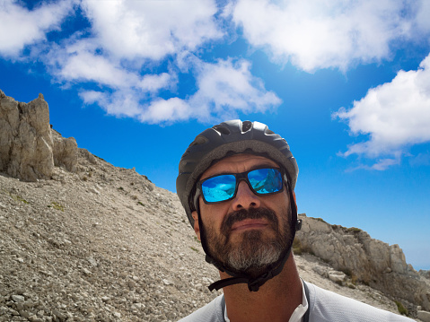 Portrait of a mountain biker with a reflection of the mountains in the sunglasses lens. The cyclist wear a protective helmet. Campo imperatore, Abruzzo, Italy.