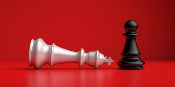 istock White chess king laying down and black pawn standing up winner on a chessboard, red background. 3D illustration. 1288451538