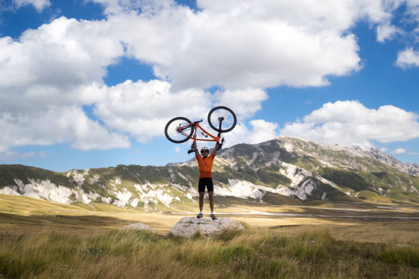 istock Mountain biker holding bike above head; scenics on background 1288451634