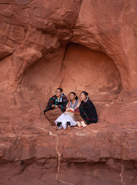 istock Three Navajo sisters sitting on a rock formation in Monument Valley - Arizona 1288452835