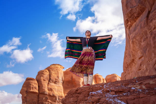 navajo junges mädchen hält eine traditionelle decke mit offenen armen auf einem felsen in arizona - navajo american culture indigenous culture women stock-fotos und bilder