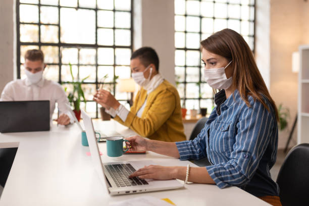 istock Young coworkers wearing protective masks while working 1288454648
