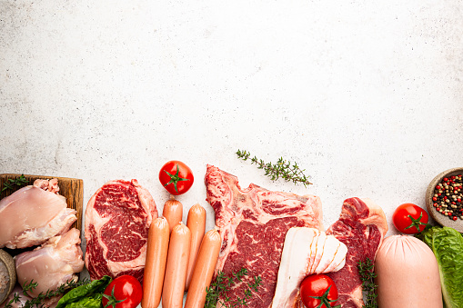 Variety of Fresh Raw meat and sausages on white background. Top view with space for your text