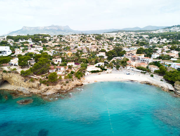 Distant view rocky coves, sandy beach, tiny bay of Benissa. Spain Distant view rocky coves, sandy beach, tiny bay of Benissa. Turquoise bright blue Sea waters hillside townscape at sunny day. Aerial photo drone point of view photography. Costa Blanca. Espana. Spain benissa stock pictures, royalty-free photos & images