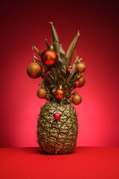 istock Golden pineapple with Christmas sunglasses on red background. 1288464851