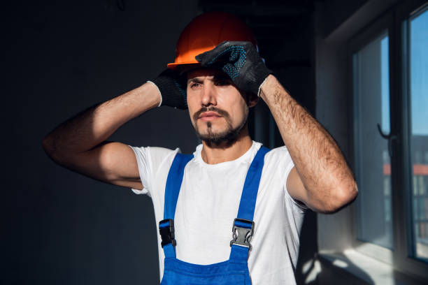 istock Bearded craftsman in overalls puts on a helmet 1288466412