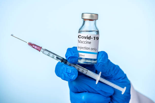 醫生或護士拿著科維德-19疫苗和注射器與她的藍色手套。 - covid 19疫苗 個照片及圖片檔