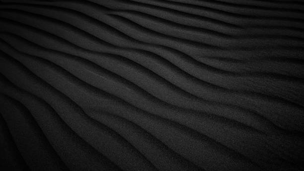 istock Black Sand dune. Black Sand beach macro photography. Background, texture, wave pattern of oceanic sand on the beach, black. Texture of beach sand. Black beach. 1288468314