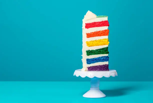 Photo of Slice of rainbow cake. Delicious multi-layered birthday cake.