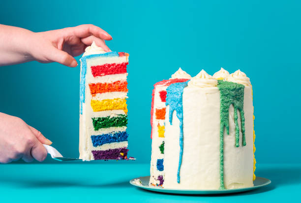 donna che prende una fetta di torta. torta arcobaleno fatta in casa su sfondo blu - torta alla crema foto e immagini stock