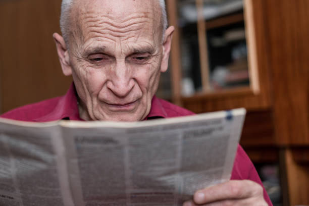 istock senior man with bad eyesight reading newspaper at home 1288472411