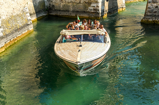 Sirmione, Lake Garda, Italy - September 2018:  Visitors to Sirmione on Lake Garda taking a trip around the moat of Scaliger Castle in a motor launch,