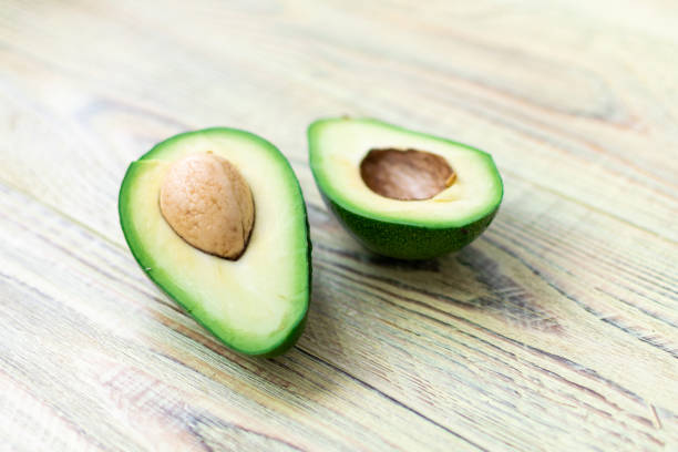 istock Avocado cut in half on a wooden background. 1288477793