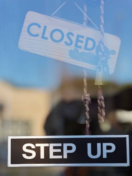 istock Closed sign with step up sign hanging right below in store window 1288488766