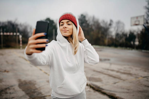 Modern young woman with cellphone making pause during jogging / exercise