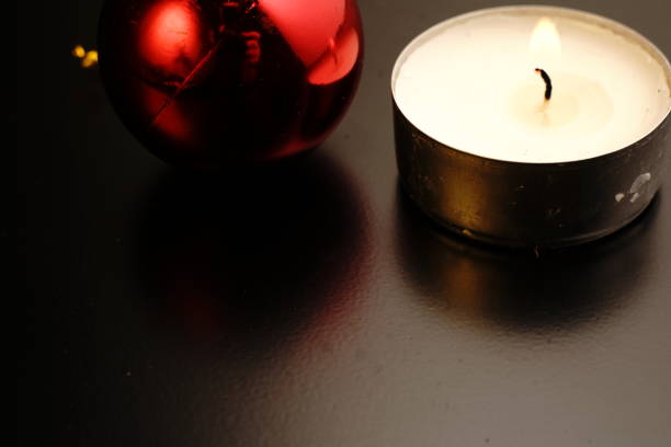 istock Candle and Christmas toy on black background. Dim lights. 1288493829