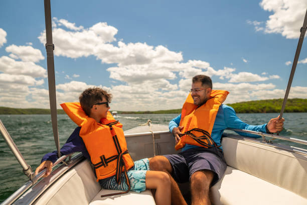 padre e figlio nei giubbotti di salvataggio che si godono il giro in motoscafo - speedboat leisure activity relaxation recreational boat foto e immagini stock