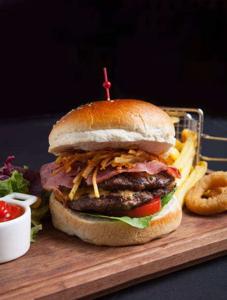 istock Gourmet burger with ham and fried onion and potatoes vertical view 1288497598