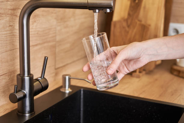 istock Woman pour clean water from tap filter into a glass 1288509679