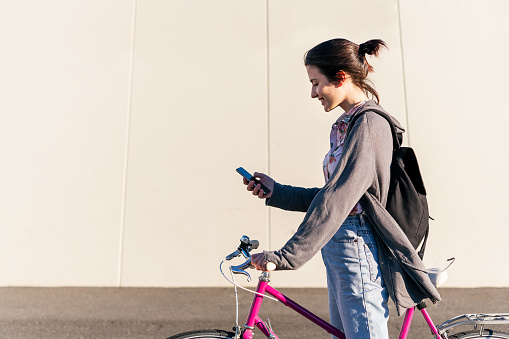 girl with pink retro bike looking her smart phone