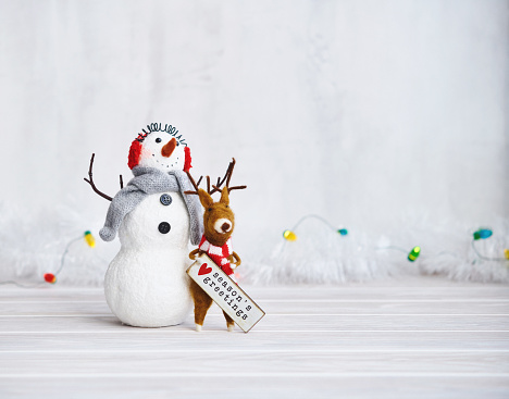 Merry christmas and happy new year greeting card . Happy snowman standing with christmas gifts on gray background