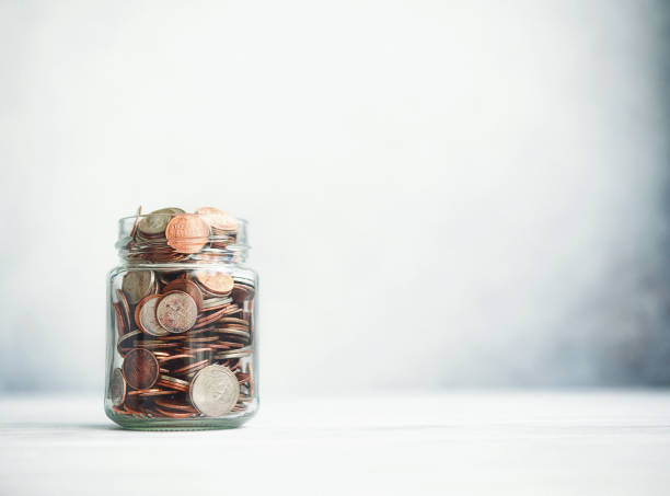 istock Change Jar Filled with Coins on Gray Background 1288514943