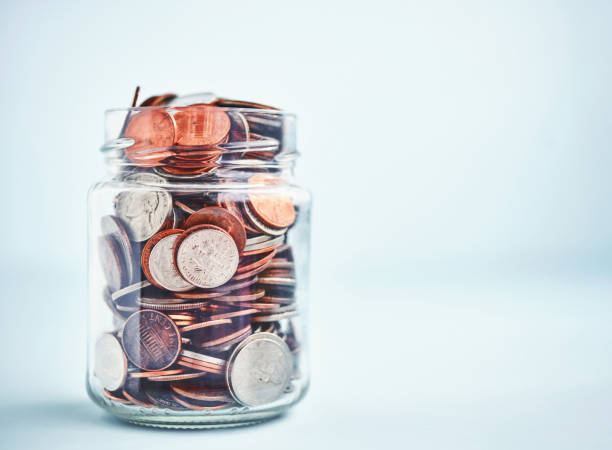 istock Change Jar Filled with Coins on Bright Blue Background 1288514948